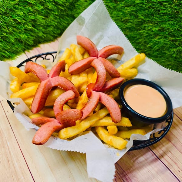 Franco's Taqueria's salchipapas, a basket of golden fries topped with sliced hot dogs and a side of sauce.