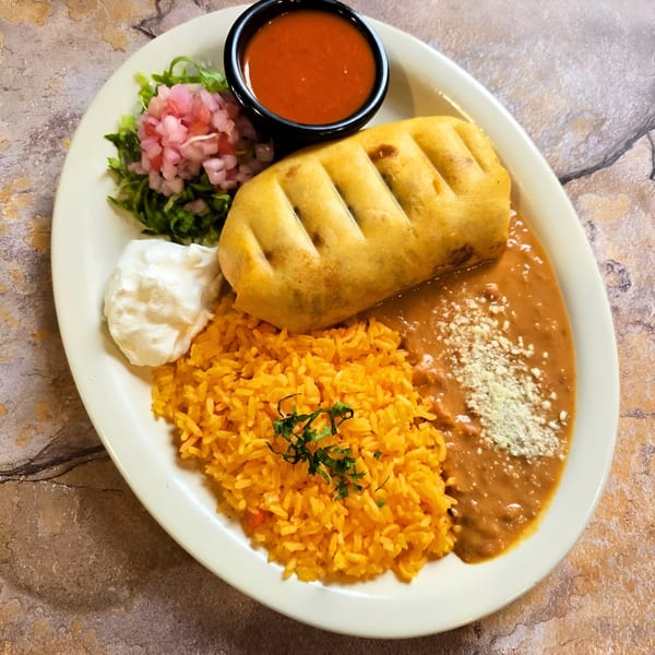 A Franco's Taqueria chimichanga with rice, refried beans, sour cream, salsa, and pickled onions.