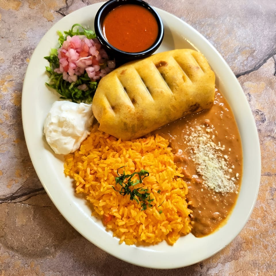 A Franco's Taqueria chimichanga with rice, refried beans, sour cream, salsa, and pickled onions.