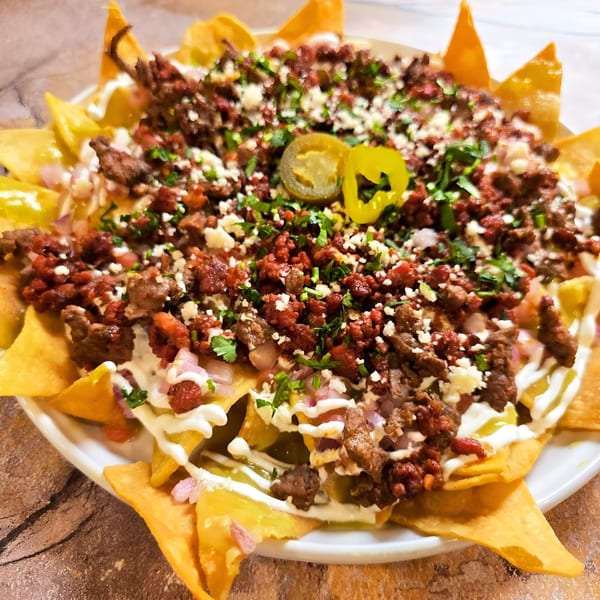 Close-up of Franco's Taqueria nachos with chorizo, steak, cheese, sour cream, cilantro, and jalapeños.